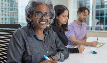 three people sitting at a table in an office meeting room